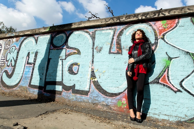 Gorgeous brunette woman posing with blue graffiti on the street.	
