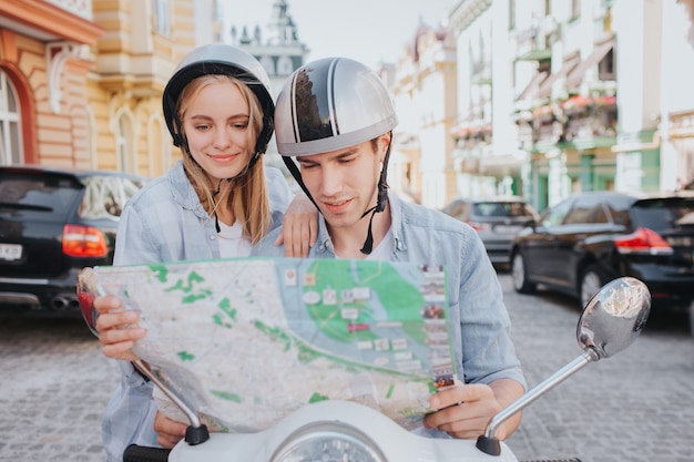 Gorgeous couple riding a motorcycling in the city and looking a map