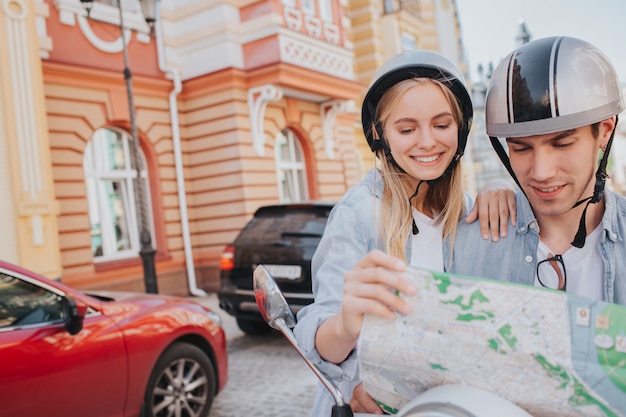 Gorgeous couple riding a motorcycling in the city and looking a map