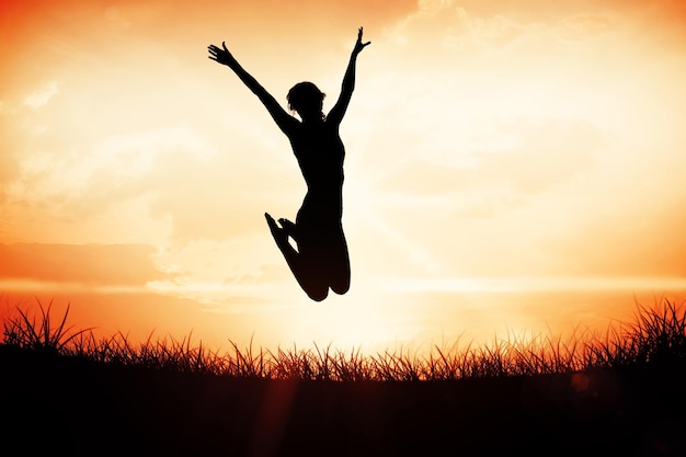 Gorgeous fit blonde jumping with arms out against orange sunrise