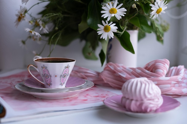 A gorgeous fragile whitepink cup of coffee on a large soft pink napkin and a pink marshmallow