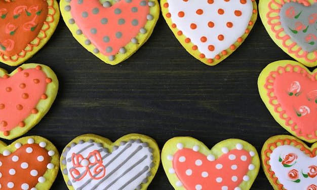 Gorgeous frames of orange and yellow heart shaped cookies on black background