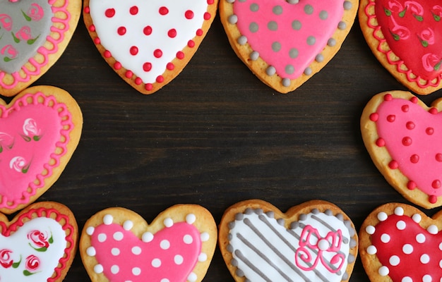 Gorgeous frames of purple pink heart shaped with adorable pattern cookies on black background