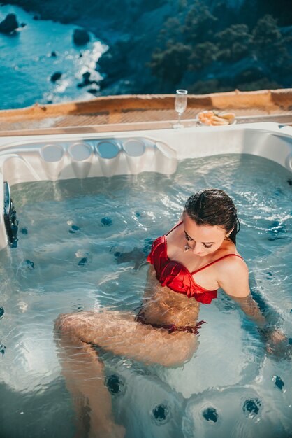 Gorgeous girl in an outdoor Jacuzzi with a beautiful view of the sea and mountains