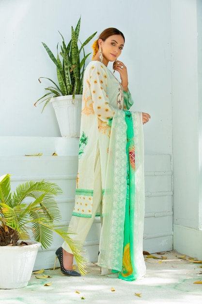 Photo gorgeous model side pose wearing traditional dress and jewelry standing with plants for photoshoot