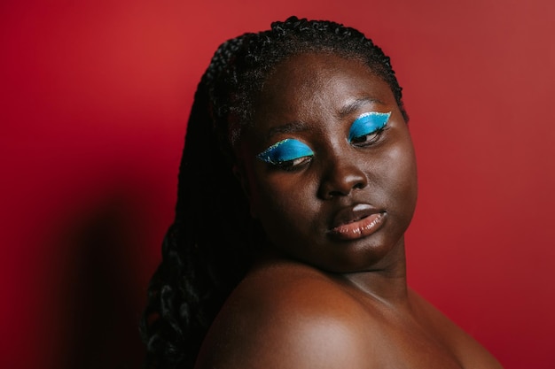 Gorgeous plus size African woman with beautiful makeup standing on red background