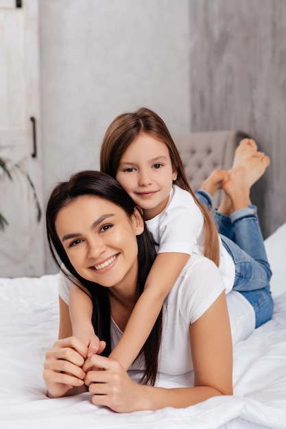 Gorgeous positive female relaxing with her lovely daughter on comfortable bed