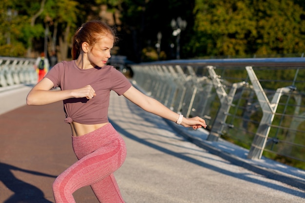 Gorgeous redhead athletic woman having stretching workout at the bridge. Space for text