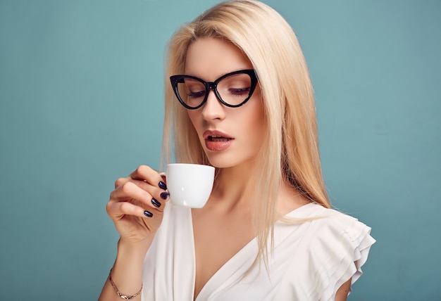 Gorgeous sensual blonde woman in white dress with cup of coffee