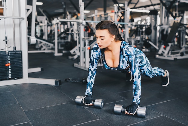 Gorgeous sexy brunette warming up and doing some push ups a the gym. Athlete builder muscles lifestyle.