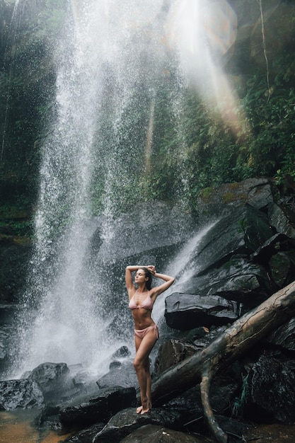 Gorgeous wet woman posing beside mighty Phnom Kulen waterfall