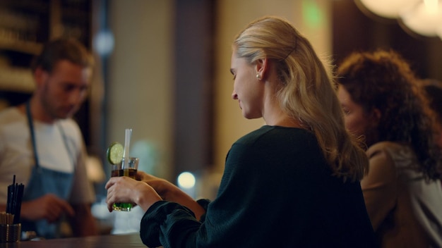 Gorgeous woman sitting with cocktail in bar Bartender smiling visitors