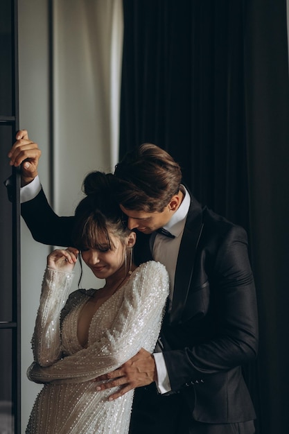 Gorgeous woman with red lips and big eyes stands with man in hotel room