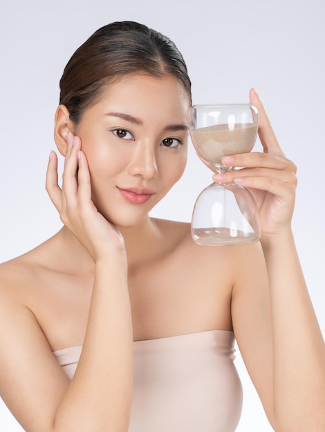 Gorgeous young woman holding an hourglass demonstrated anti aging concept