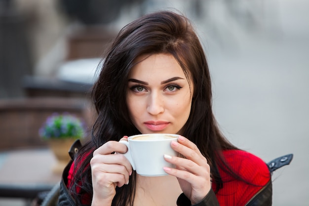 Gorgeous young woman with cup of coffee in city street