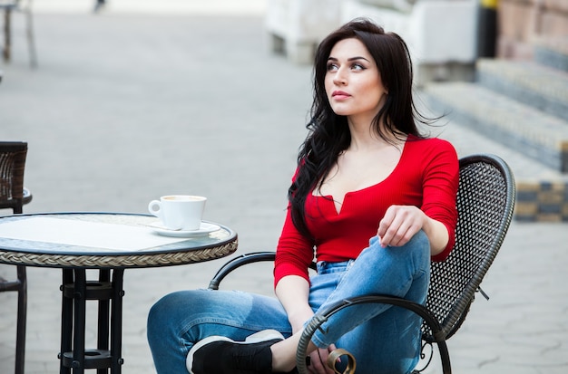 Gorgeous young woman with cup of coffee in city street