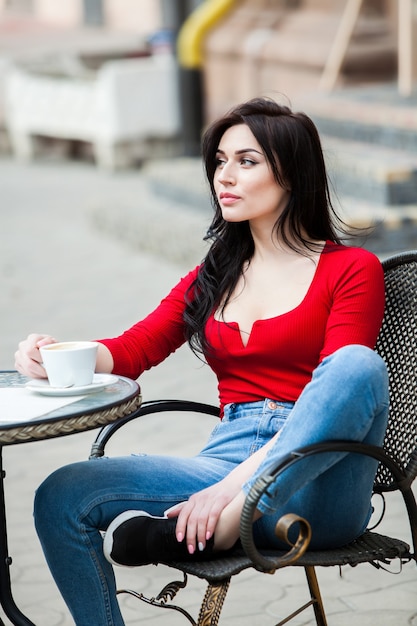 Gorgeous young woman with cup of coffee in city street