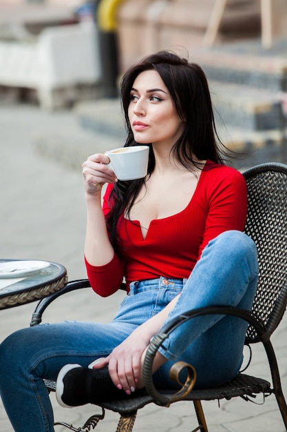 Gorgeous young woman with cup of coffee in city street