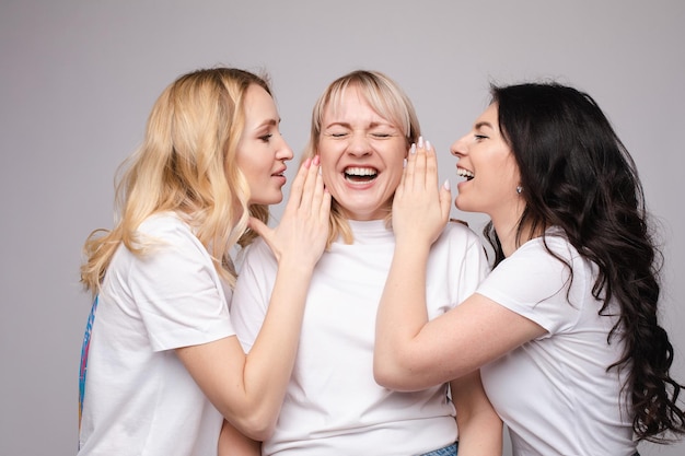 Gossiping girls whispering a secret to their friend