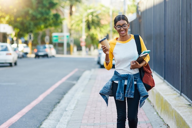 Got my coffee to commute to college Cropped shot of a young female student commuting to college in the city