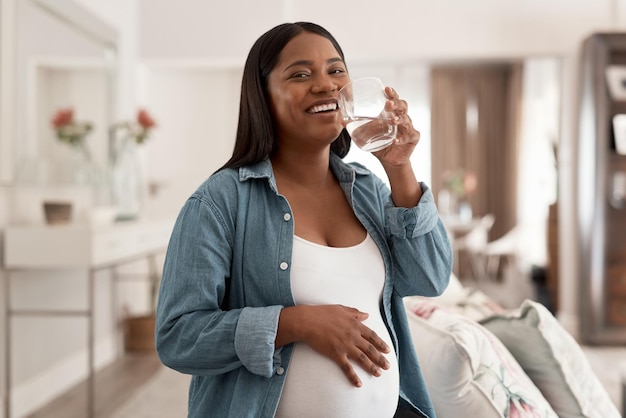 Got to stay hydrated for good health Portrait of a pregnant woman drinking a glass of water at home