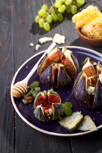 Gourmet appetizer of figs with goat cheese,walnuts and honey on ceramic plate 