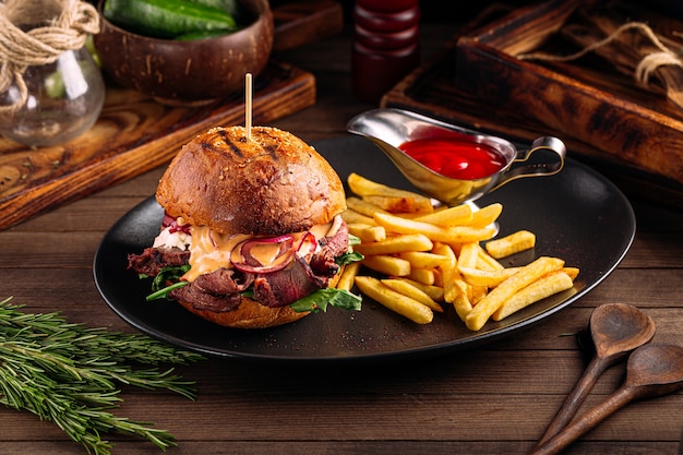 Gourmet burger with beef meat and french fries on the wooden table