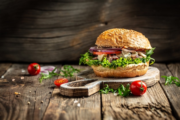 Gourmet burger with blue cheese and arugula on rustic wooden surface