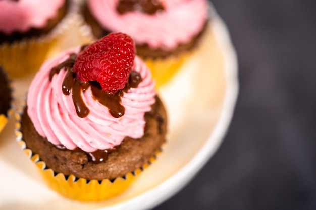 Gourmet chocolate raspberry cupcakes drizzled with chocolate ganache and topped with a fresh raspberry