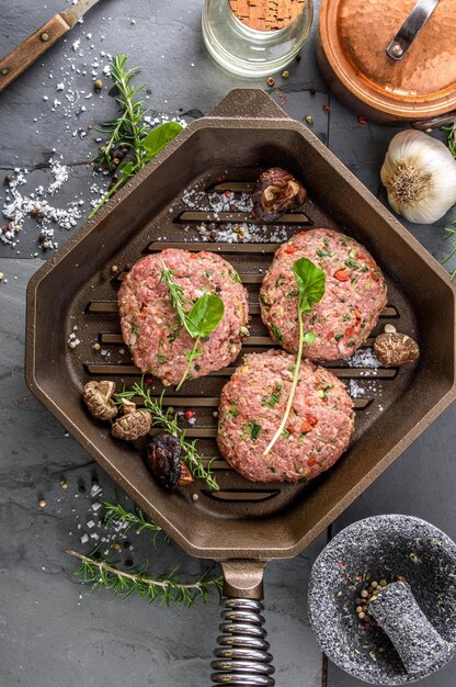 Gourmet Creation Top View of Raw Hamburger Patties with Spices Sizzling in a Cast Iron Pan Awaiting