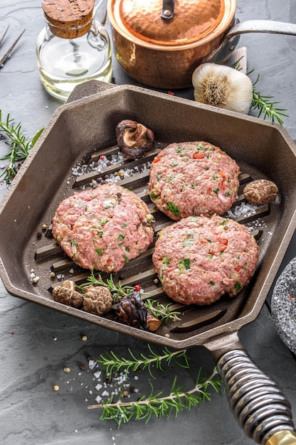 Gourmet Creation Top View of Raw Hamburger Patties with Spices Sizzling in a Cast Iron Pan Awaiting