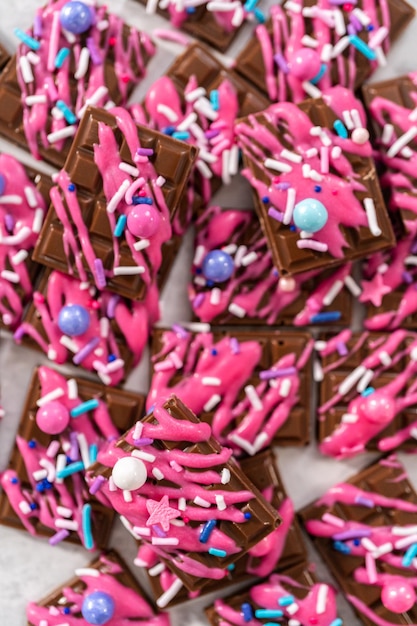 Gourmet dark mini chocolates with drizzled pink chocolate and fancy sprinkles on top.