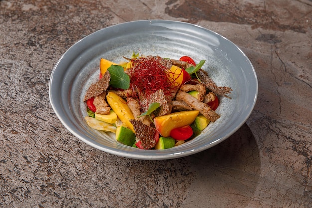 Gourmet dish with vibrant veggies on a gray plate