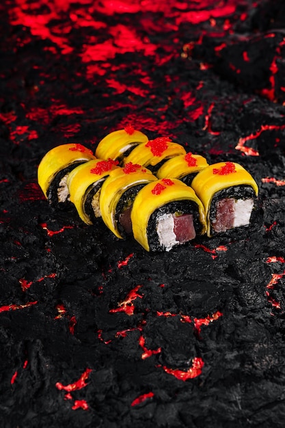 Gourmet sushi roll on fiery black texture