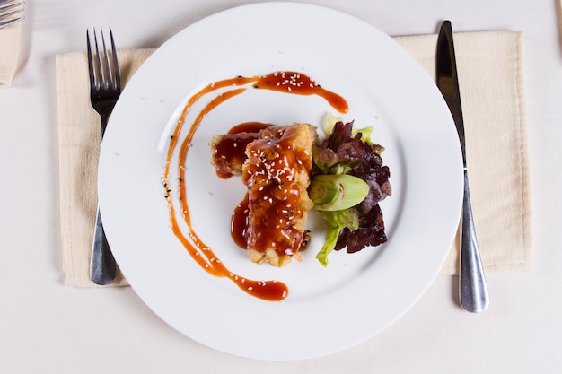 Gourmet Tasty Main Dish on White Round Plate with Utensils on Sides Served on White Table for the Guest at the Restaurant.