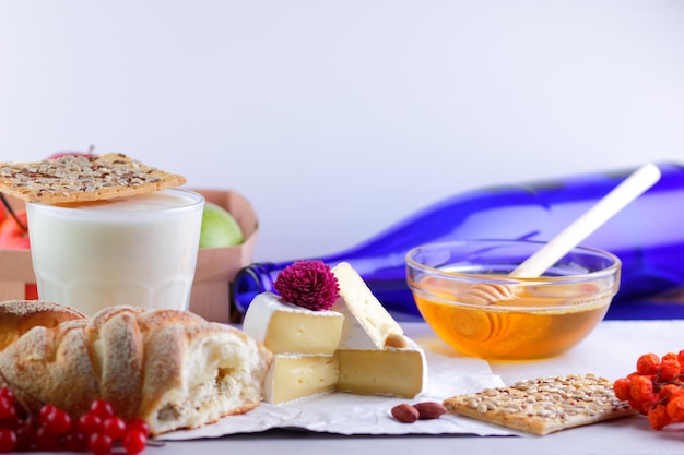 Gourmet white brie or camembert cheese with berries honey and nuts on a white parchment Still life of cheese fruit and a blue bottle on a blurred background Closeup