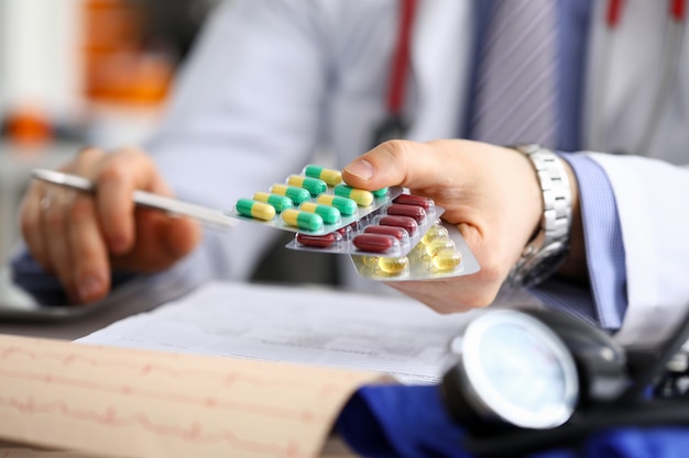 GP in clinic holding pack of different blisters close-up