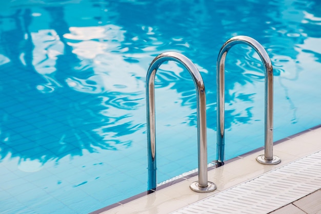 Grab bars ladder in the blue swimming pool