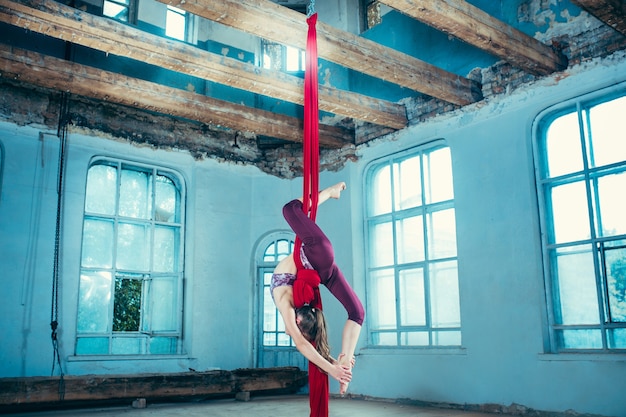 Graceful gymnast performing aerial exercise at loft