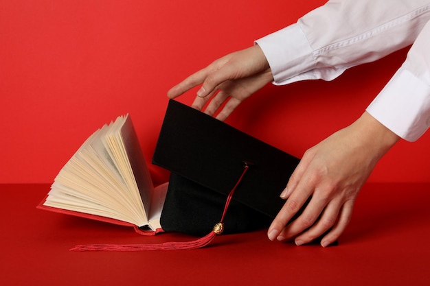 Graduate hat and books on a red background