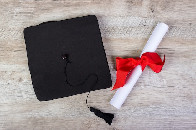 Graduation cap, hat with degree paper on wood table graduation concept