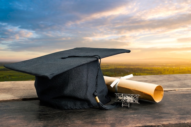 Graduation cap, hat with degree paper on wooden table 