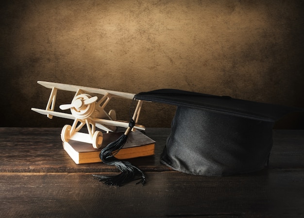 Photo graduation cap, hat with wood toy airplane on wood table