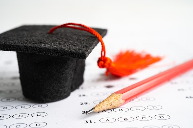 Graduation gap hat and pencil on answer sheet background Education study testing learning teach concept