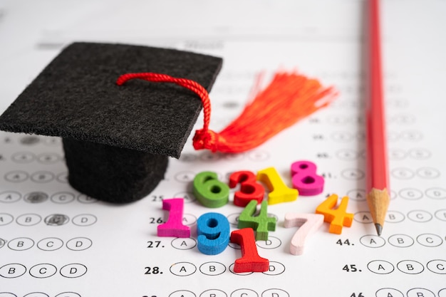 Graduation gap hat and pencil on answer sheet background Education study testing learning teach concept