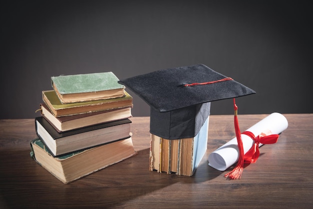 Graduation hat book and diploma on the wooden table