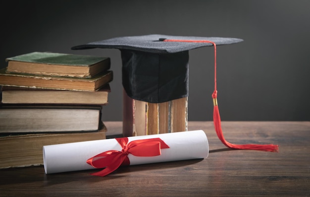 Graduation hat, book and diploma on the wooden table.