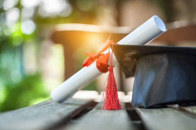 Graduation hat and diploma on wooden background