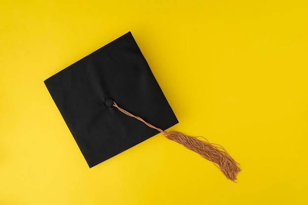 Graduation hat on yellow background Student hat Top view