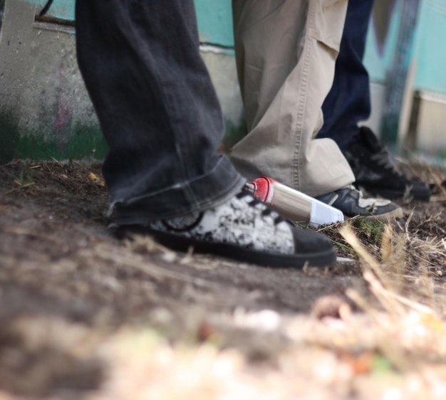 Graffiti hip hop and shoes of friends at wall for fashion street art and creative Urban relax and grunge style with sneakers of group of teenagers in park for cool trendy and spray can